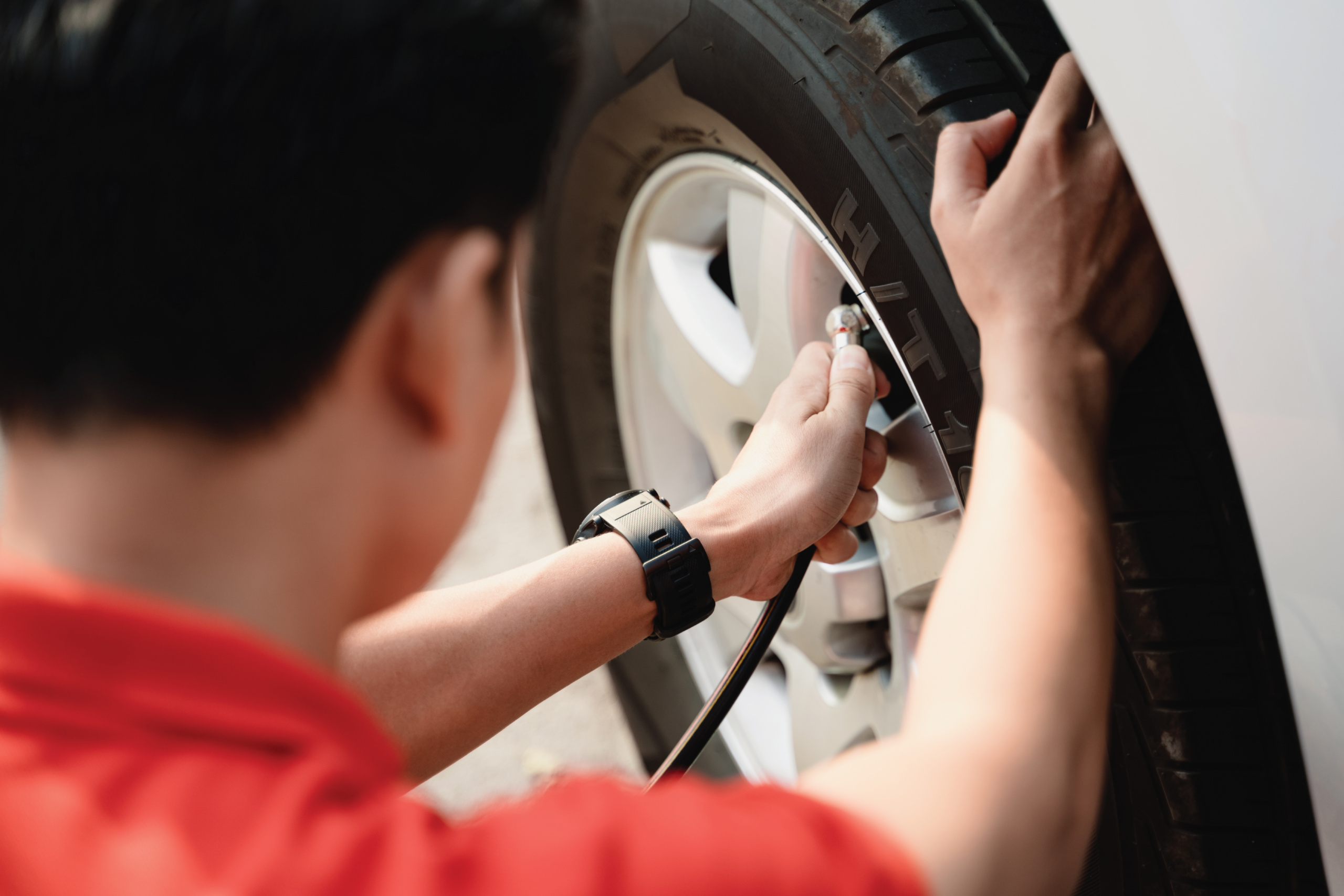 Driver inspecting car tyres as part of a UAE summer safety checklist